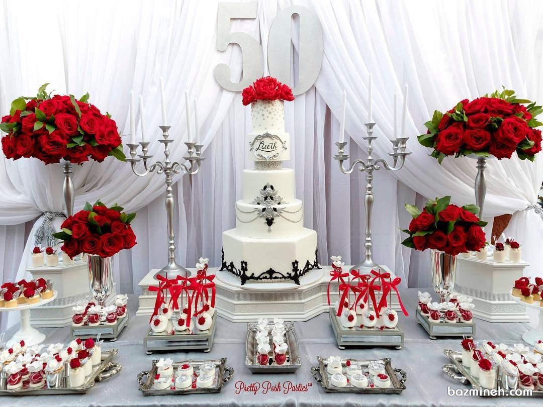 دیزاین میز پذیرایی جشن تولد پنجاه سالگی با تم سفید قرمز همراه با گل آرایی رزهای قرمز