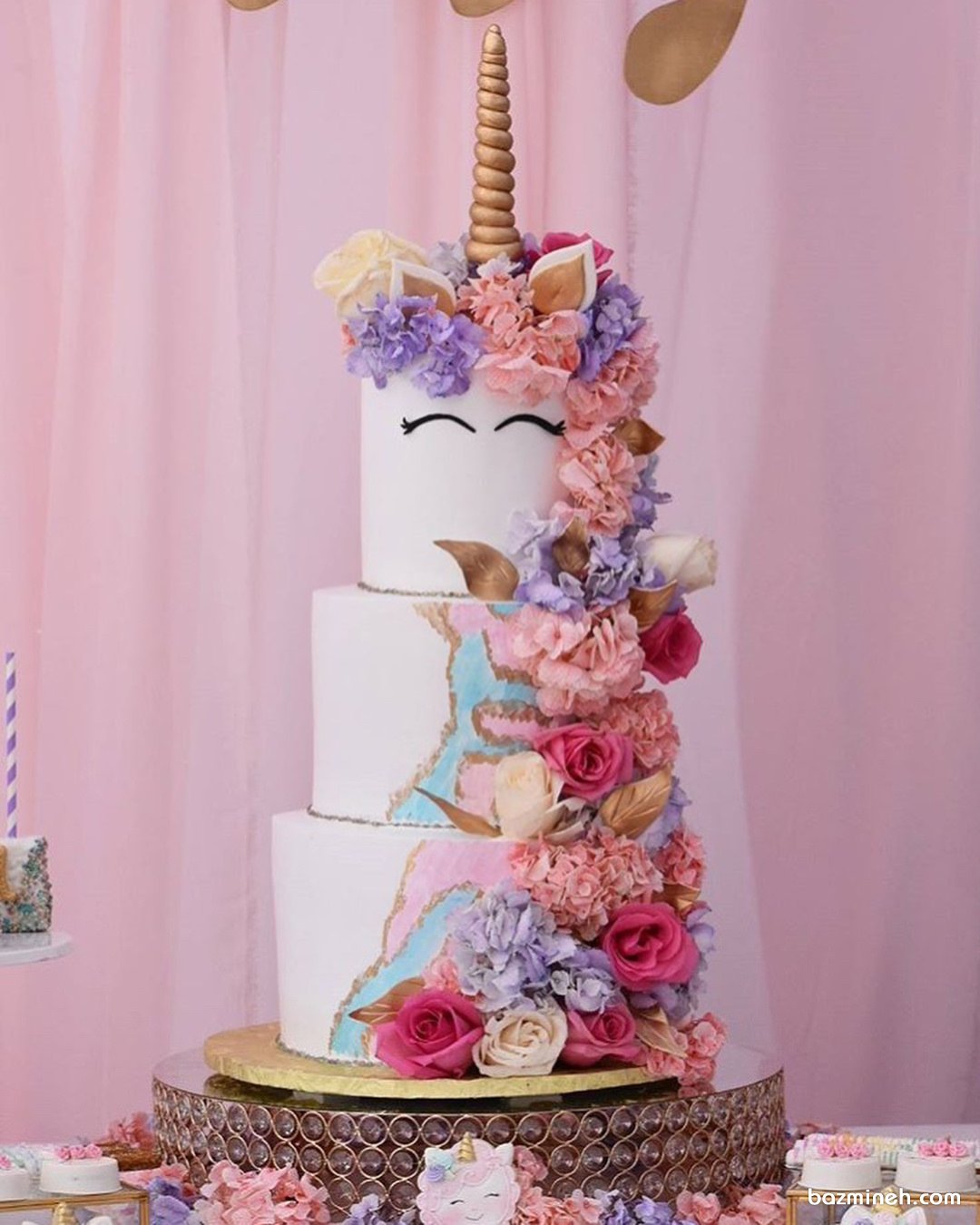 کیک چند طبقه جشن تولد دخترانه با تم اسب تک شاخ (Unicorn) تزیین شده با گل های طبیعی صورتی یاسی
