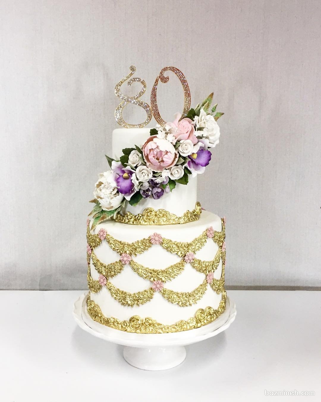کیک لوکس جشن تولد بزرگسالان تزیین شده با طرح های طلایی و گل های مصنوعی