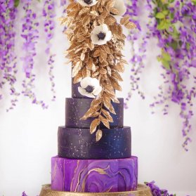 کیک چند طبقه جشن نامزدی یا سالگرد ازدواج با تم طلایی بنفش تزیین شده با گل های کرم طلایی