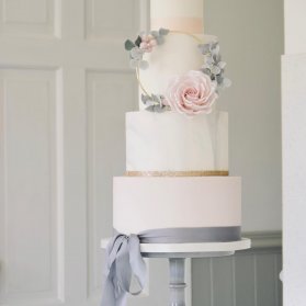 کیک چند طبقه فانتزی و رویایی جشن نامزدی یا عروسی با تم سفید طوسی صورتی تزیین شده با گل و ربان