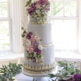 کیک چند طبقه جشن نامزدی یا سالگرد ازدواج با تم یاسی طلایی تزیین شده با گل های تزیینی صورتی یاسی
