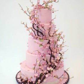 کیک چند طبقه فانتزی جشن تولد دخترانه یا سالگرد ازدواج با تم صورتی تزیین شده با شکوفه های بهاری