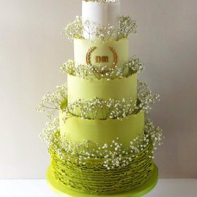 کیک چند طبقه جشن تولد با تم سفید سبز تزیین شده با شکوفه های ریز بهاری