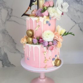 کیک دو طبقه جشن تولد دخترونه با تم صورتی طلایی تزیین شده با گل های رز طبیعی و ماکارون