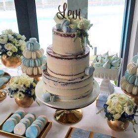 کیک سه طبقه و ماکارون های خوش مزه جشن تولد بزرگسال با تم سفید آبی تزیین شده با گل های رز طبیعی 