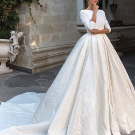 لباس عروس ساده و شیک و پوشیده آستین دار با یقه قایقی بسته و دامن کلوش دنباله دار مناسب برای عروس خانم های محجبه