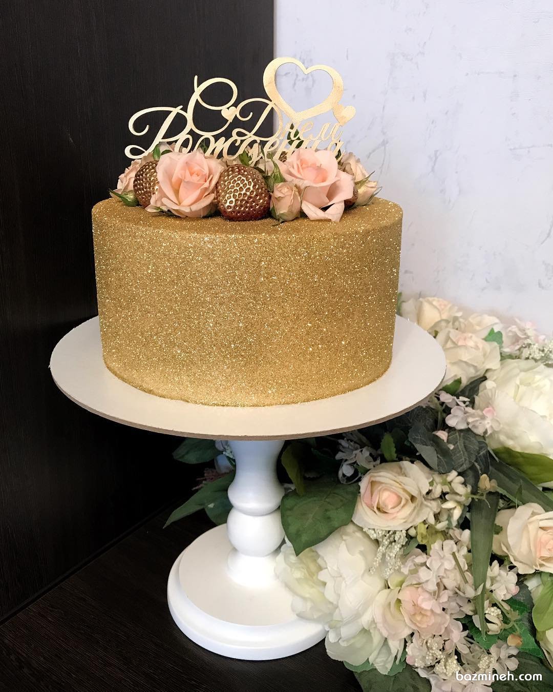 مینی کیک زیبای جشن تولد بزرگسال یا جشن سالگرد ازدواج با روکش شاینی طلایی تزیین شده با گل های رز طبیعی و توت فرنگی 