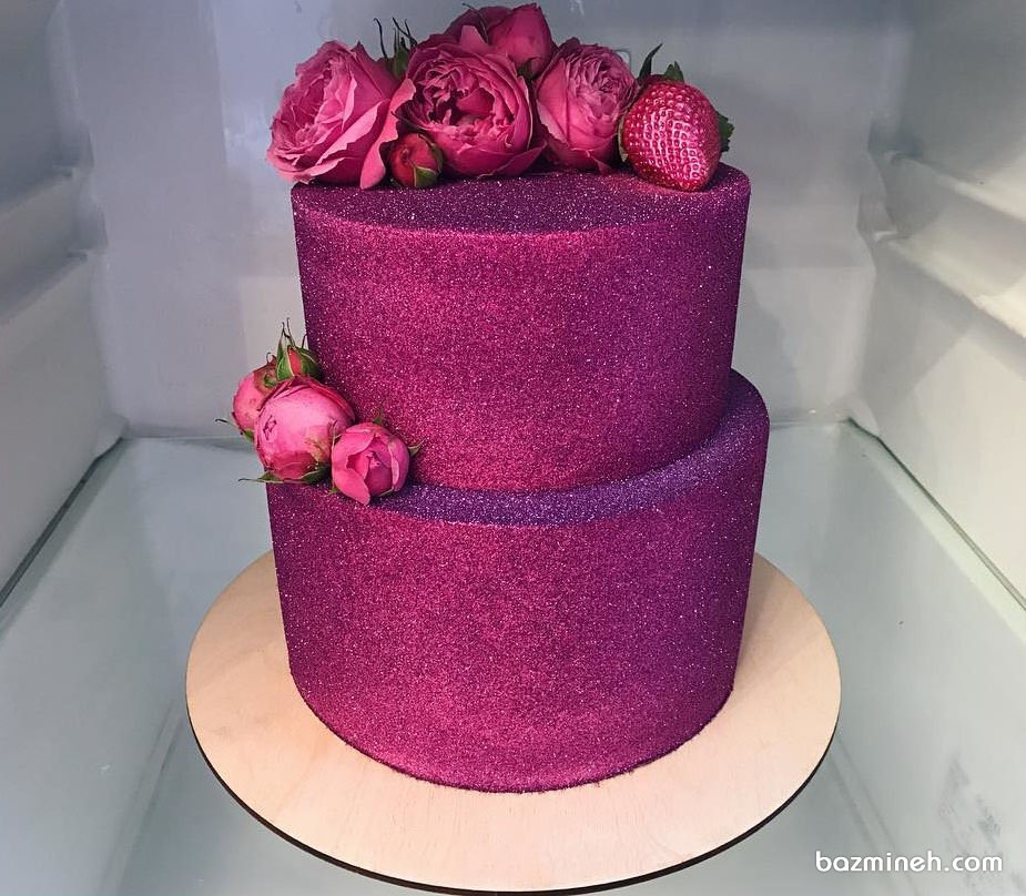 کیک دو طبقه جشن تولد بزرگسال یا سالگرد ازدواج با روکش شاینی سرخابی تزیین شده با گل های طبیعی و توت فرنگی