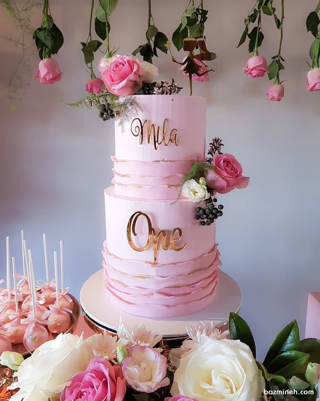 کیک دو طبقه خامه ای جشن تولد دخترونه با تم صورتی طلایی و دیزاین گلهای رز طبیعی