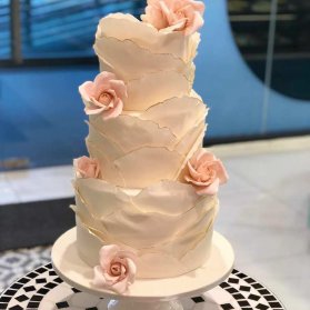 کیک چند طبقه خامه‌ای جشن نامزدی یا سالگرد ازدواج تزیین شده با گلهای فوندانت گلبهی