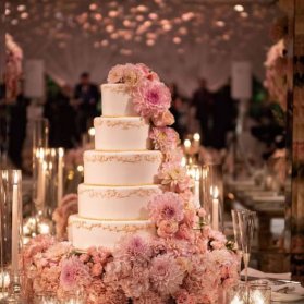 کیک بزرگ جشن نامزدی یا عروسی با تزیین گلهای طبیعی و تم رنگی صورتی کرم 
گل آرایی و استفاده از گل های طبیعی یا گل های شکری در کیک های نامزدی و عروسی بسیار متداول است و یکی از شیکترین و زیباترین روش های دکوراسیون کیک های عقد و عروسی است. در این ایده با توجه به نوع رنگ بندی سایر المان های دکوراسیون عروسی، از گل های سفید وصورتی بهره برده شده که یکی از بهترین رنگ بندی ها برای مراسم عروسی میباشد.