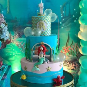 کیک چند طبقه جشن تولد دخترونه با تم پری دریایی
یکی از رنگ هایی که با دیزاین پری دریایی برای تولدهای دخترانه همخوانی دارد، رنگ آبی فیروزه ای یا سبزآبی است که جلوه ای بسیار جذاب به تولد می دهد. رنگ آبی فیروزه ای نماد ارامش و خوش شانسی است که انتخاب ان برای تولدهای دخترانه بسیار بجاست